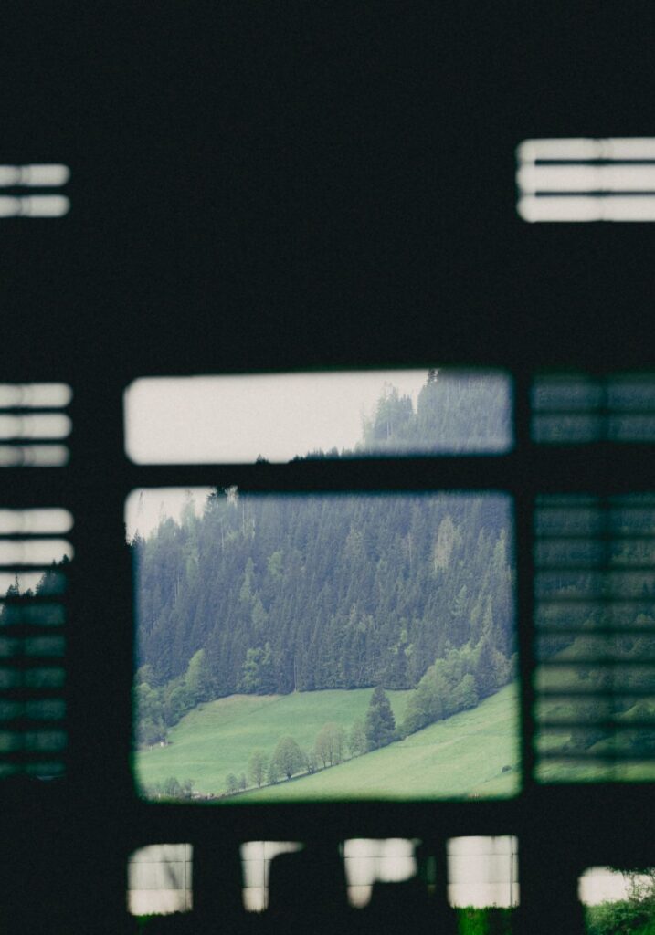 View of green hills and a forested landscape framed by a dark window opening.