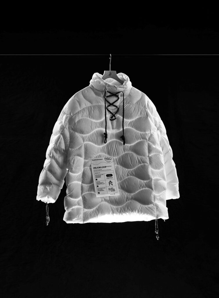 White quilted down jacket with wave-pattern stitching and lace-up collar detail, hanging against a black background.
