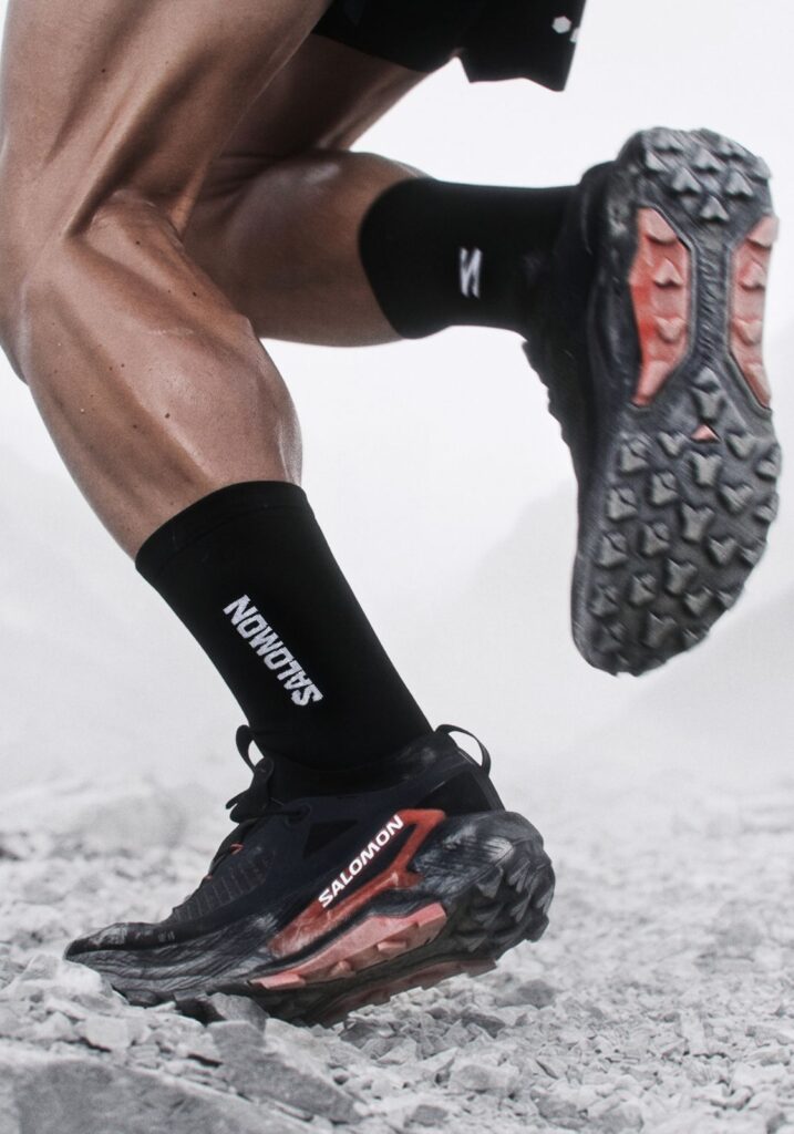 Close up of a person running uphill in black Salomon shoes