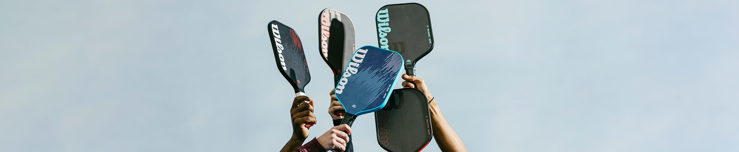 People rising pickleball rackets in the air.