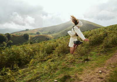 Woman jumping on top of a hill in Peak Performance clothing