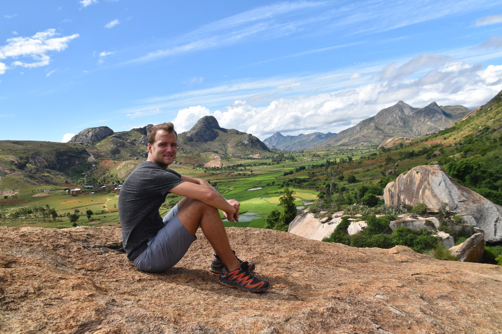 Marco Edner sitting on top of a mountain in Madagascar wearing Salomon shoes.