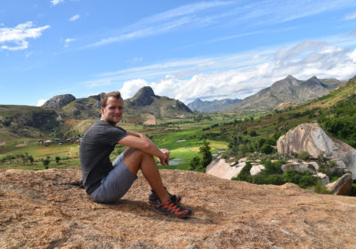 Marco Edner sitting on top of a mountain in Madagascar wearing Salomon shoes.
