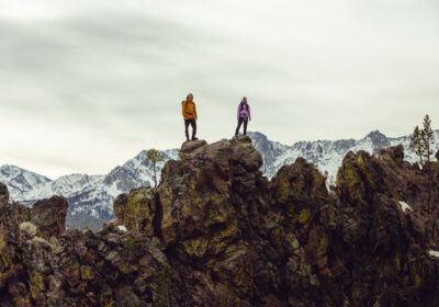 Two hikers stand on a cliff in Arc'teryx clothing
