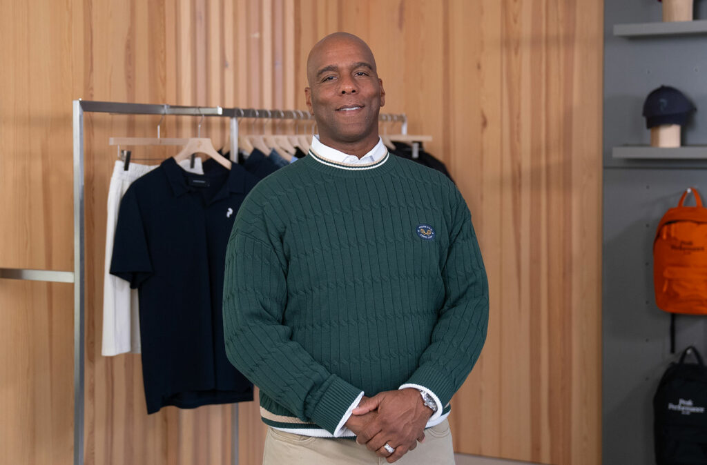 Portrait of Andrew Page, wearing a green sweater, arms folded in front.