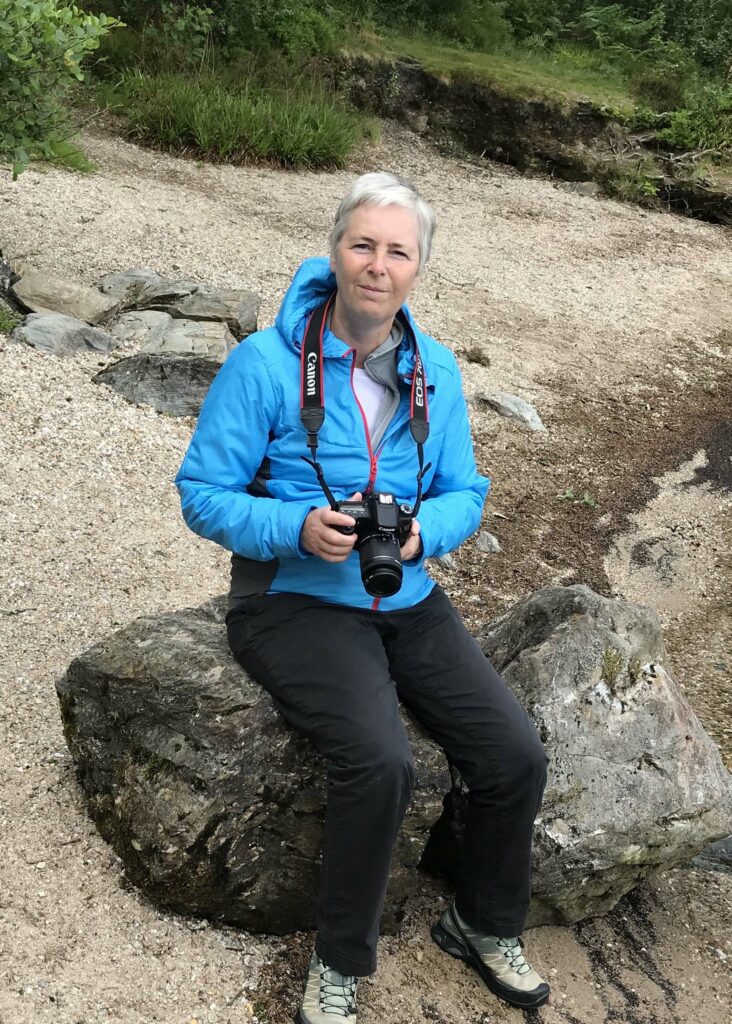 Carol Brodie sitting on a rock outdoors.