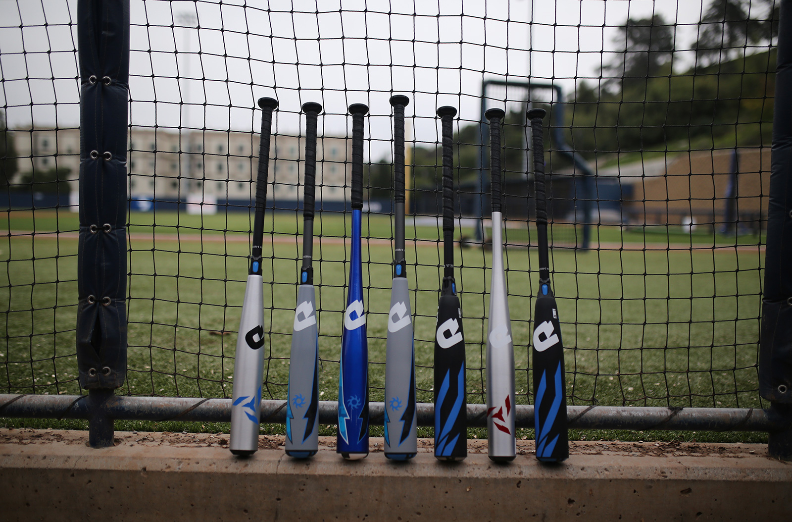 Seven baseball bats leaning against a net.