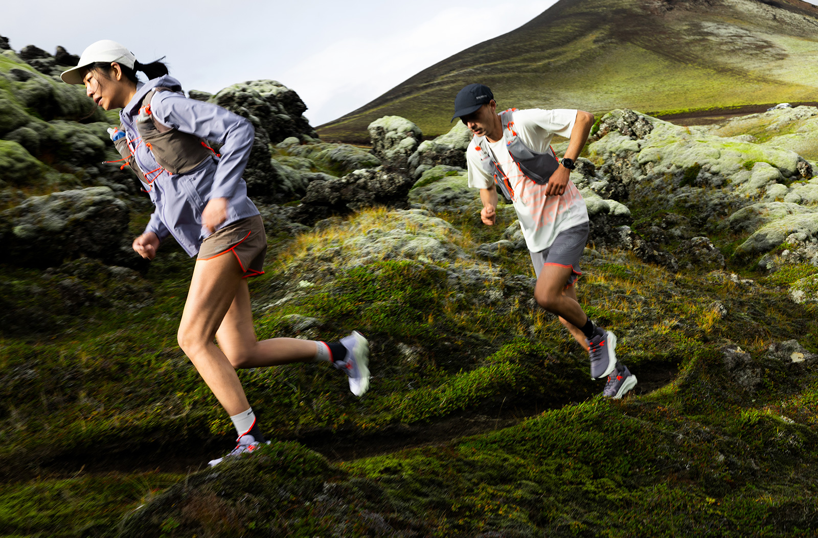 Two people running on green hills.