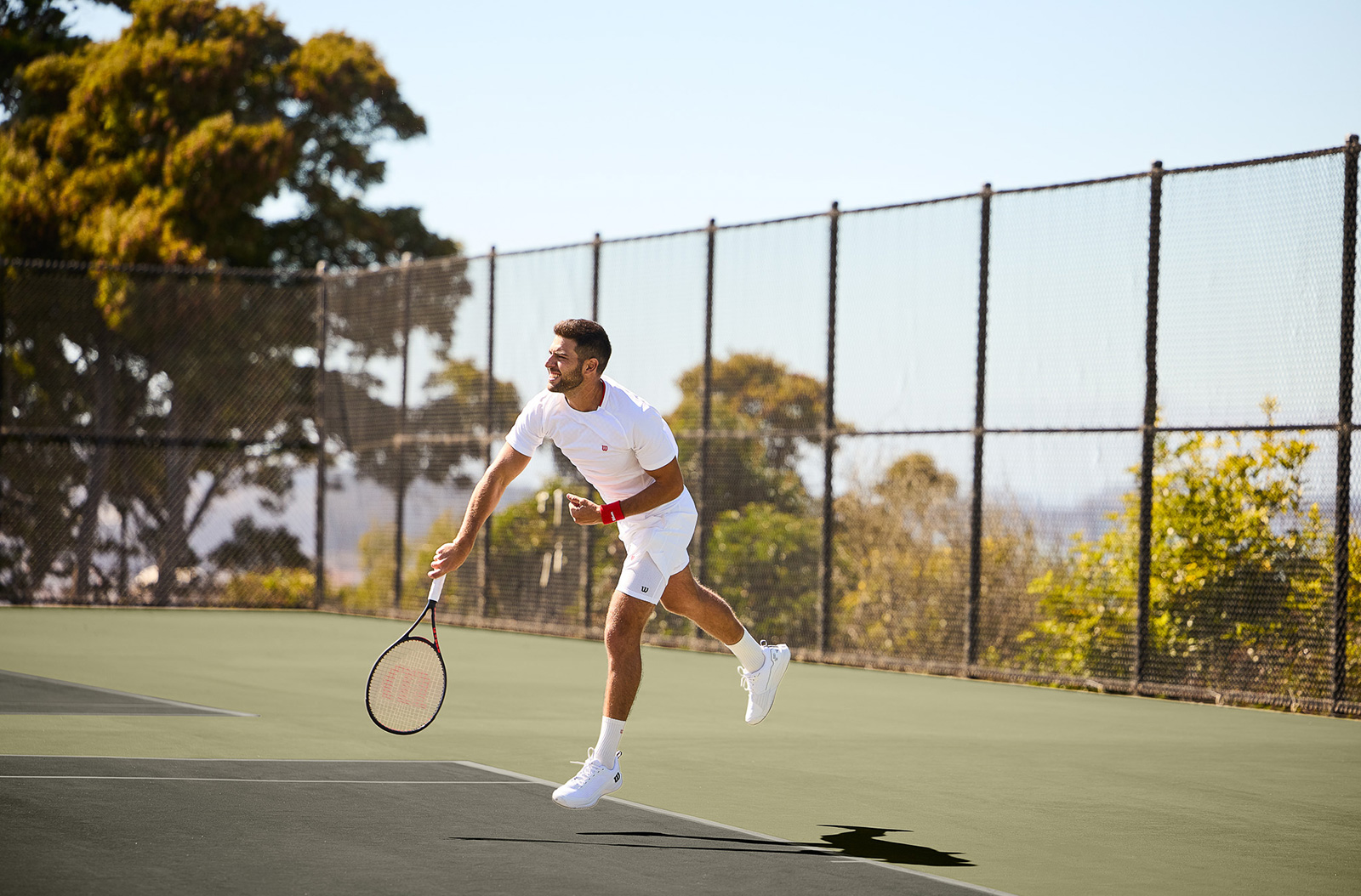 A person playing tennis outdoors.